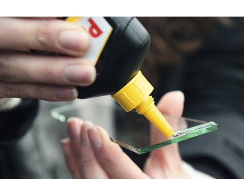 Iemand brengt lijm aan op een stuk glas