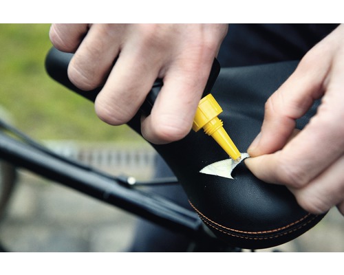 Iemand repareert een fietszadel met lijm.