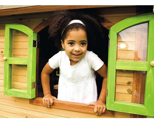 Een kind kijkt uit het raam van een houten speelhuis.