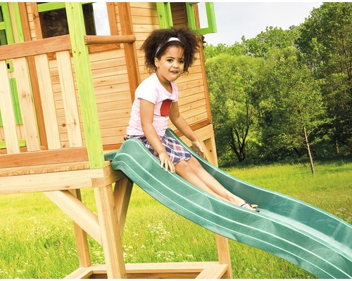 Meisje glijdt van een speeltoren glijbaan in de tuin