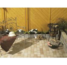 Aangelegde tuin met zitje, vuurplaats en stapel hout op bestrating