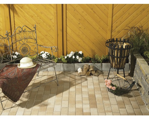 Aangelegde tuin met zitje, vuurplaats en stapel hout op bestrating