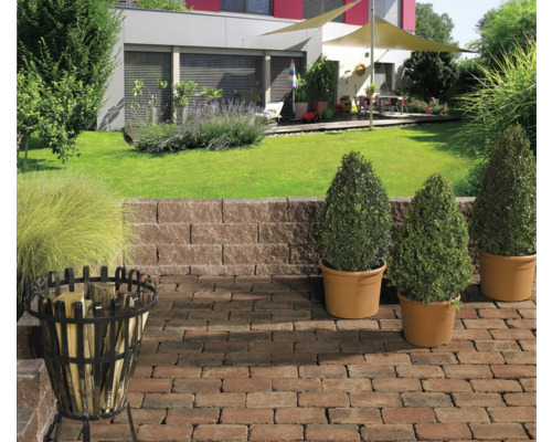 Aangelegde tuin met planten, bestrating, steunmuur en vuurkorf