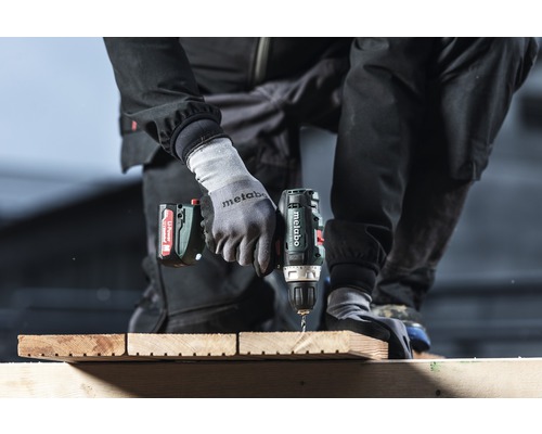 Iemand boort met een Metabo accuschroefboormachine in een houten plank.