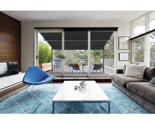 Woonkamer met bank, fauteuil, tapijt en terrasdeur met rolluik