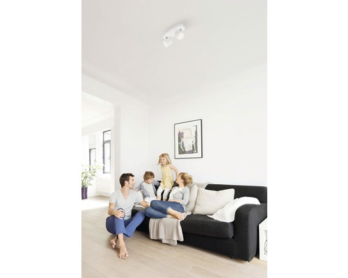 Scene van een woonkamer met een gezin onder een plafondlamp met twee spots.