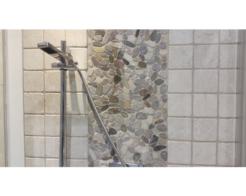 Gedetailleerde opname van een douchekop tegen een achtergrond van kiezels en tegels