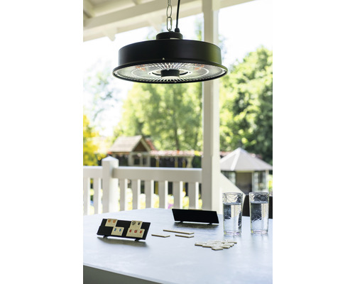 Scene met een hangende terrasverwarmer boven een tafel met glazen en een spel buitenshuis