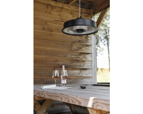 Scene met een terrasverwarmer aan het plafond boven een houten tafel met wijn en een krant in een tuinhuis