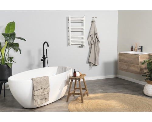 Lichte badkamer met ligbad, wastafel, handdoekradiator en decoraties voor een vriendelijke sfeer.