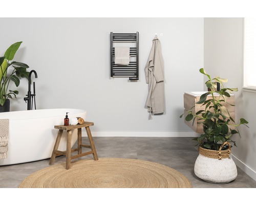 Lichte badkamer met bad, wastafel, handdoekradiator en kamerplanten voor een vriendelijke sfeer