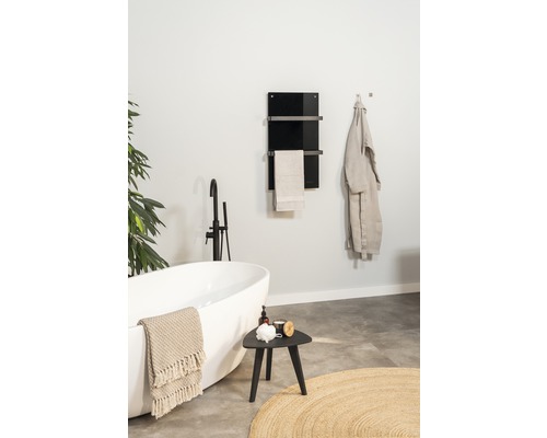 Badkamer met bad, kruk en handdoekverwarmer aan de muur
