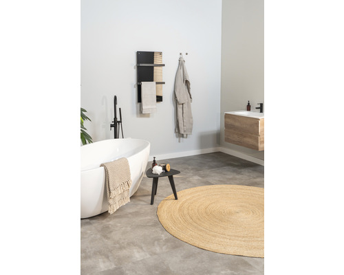 Badkamer met vrijstaand bad, handdoekradiator, kruk en rond vloerkleed