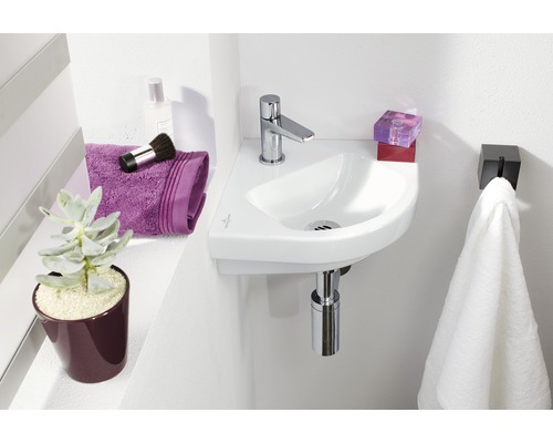 Compacte badkamer met hoekwastafel, kraan, handdoek en accessoires