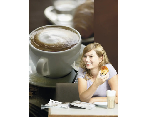 Een vrouw zit aan een tafel met koffie, een chocoladecroissant en een tijdschrift.