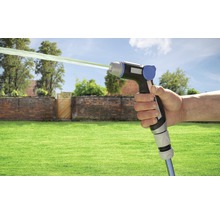 Hand houdt tuinspuit met waterstraal voor tuinscène