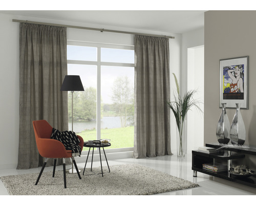 Woonkamer met gordijnen, fauteuil, vloerlamp en decoratie