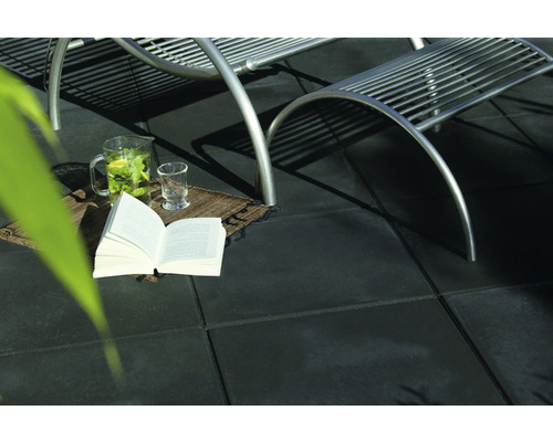 Terras met terrastegels, tuinligstoel, boek, karaf en glas