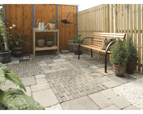 Tuinscene met tuinbank, plantentafel, planten en stenen vloer