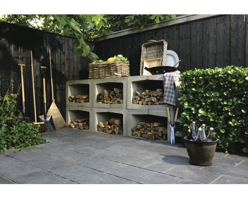 Tuin met houten rek, tuingereedschap en bestrating.