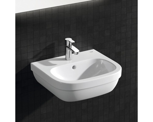 Witte wandwastafel met kraan tegen een donkere achtergrond