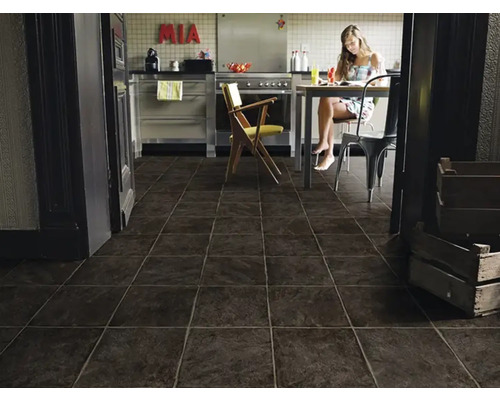 Moderne keuken met donkere tegelvloer en een vrouw aan de eettafel.