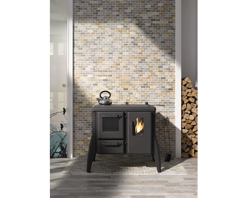 Interieurfoto met een fornuis, een theeketel, brandhout en een gemetselde muur