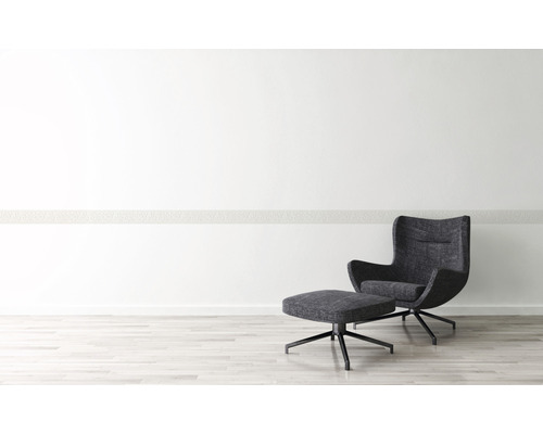 Modern interieur met fauteuil en voetenbank op een lichte houten vloer voor een witte muur