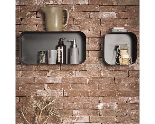 Badkamerdecoratie met planken, zeep, lotion en kan tegen een bakstenen muur