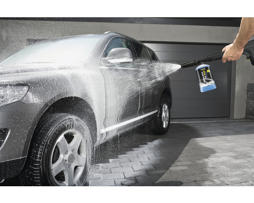 Een grijze auto wordt gereinigd met een hogedrukreiniger.