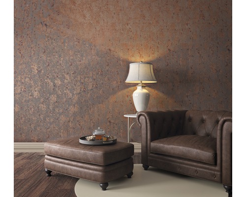 Woonkamer met Chesterfield-fauteuil, ottomane, tafellamp en patroonbehang voor een gezellige sfeer