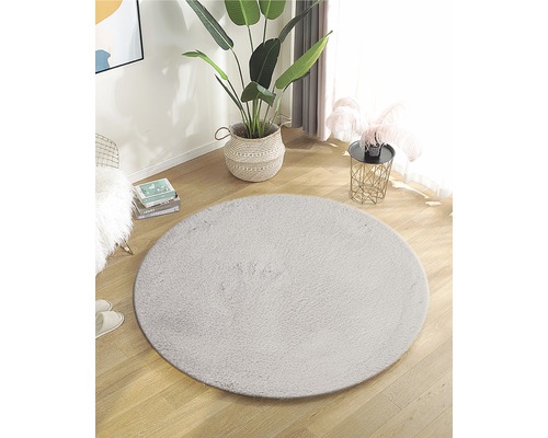 Inrichting met rond kunstvezel tapijt op een houten vloer in een heldere ruimte.