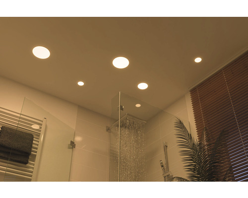 Moderne badkamer scène met LED inbouwspots in het plafond, douche met glazen wand en radiator.