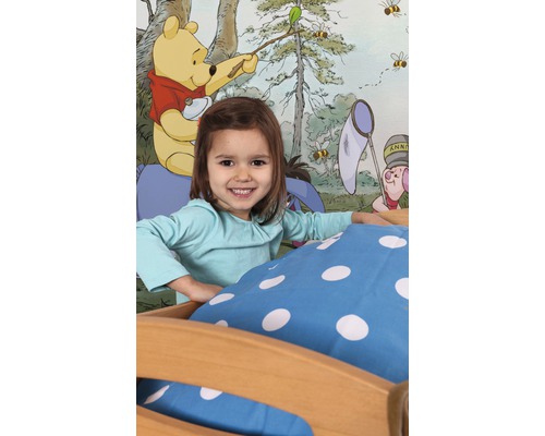 Meisje in bed voor een behang met Winnie de Poeh motief.