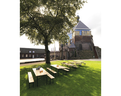 Scene met biertafels en banken op een gazon voor een historisch gebouw