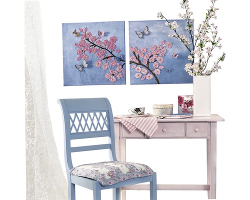 Decoratieve scène met een blauwe stoel, een roze tafel en twee schilderijen met bloemmotieven aan de muur