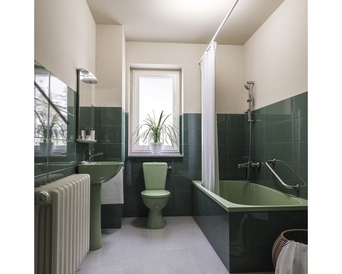 Badkamer met ligbad, wastafel, toilet, radiator, raam en planten