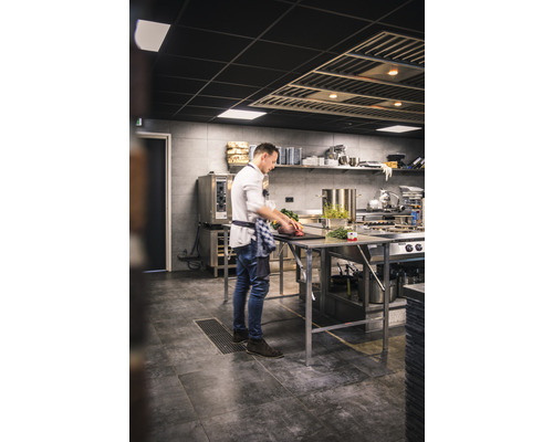 Een kok bereidt gerechten in een professionele keuken op een roestvrijstalen werkbank.