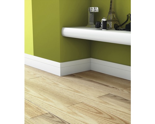 Interieurfoto van een kamer met een laminaatvloer, witte plinten en een witte wandplank