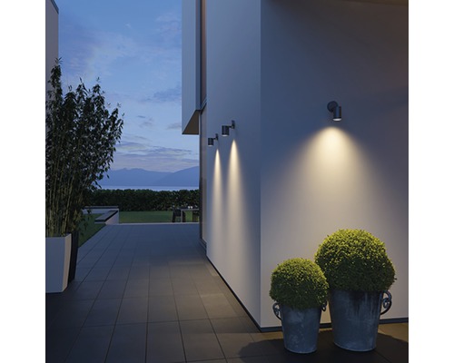 Buitenruimte met wandlampen, planten en avondlucht