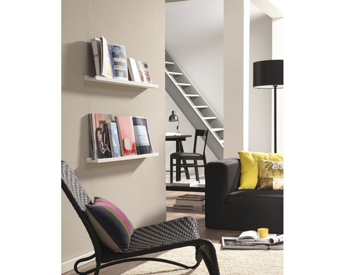 Woonkamer met leeshoek, bestaande uit twee witte wandplanken met boeken, een fauteuil, een bank en een vloerlamp.