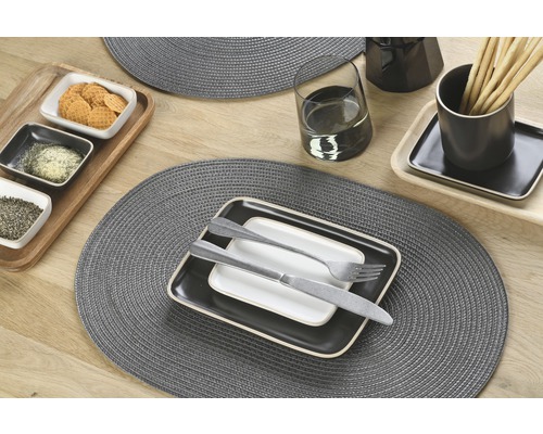 Tafeldecoratie met placemats, servies, bestek, glazen en eten op een houten tafel.
