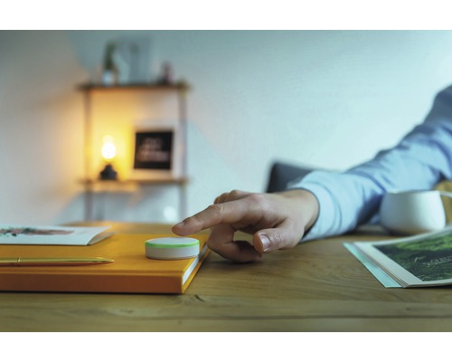 Scene met een bedieningselement op een oranje notitieboek, dat door een persoon wordt bediend.