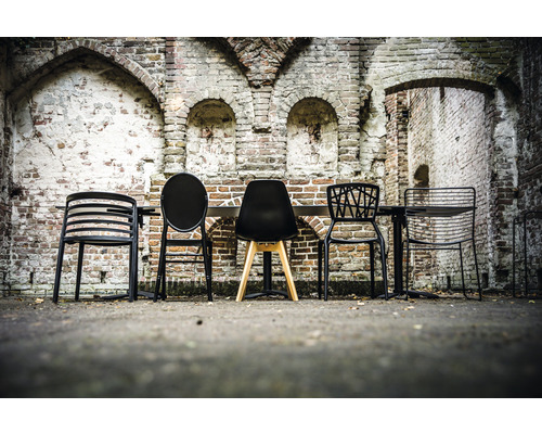 Diverse stoelen en een tafel voor een bakstenen muur