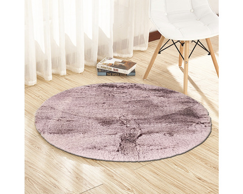 Rond vloerkleed op houten vloer met stoel en boeken