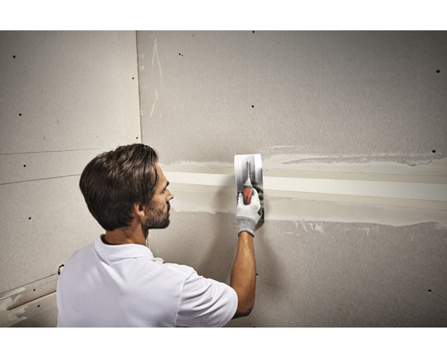 Ambachtsman plamuurt een gipsplaten muur met een plamuurmes