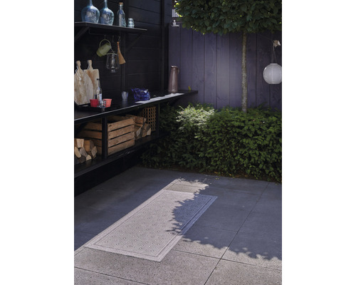 Buitenruimte met houtopslag, werkblad en een vloerkleed met motief op de grond.