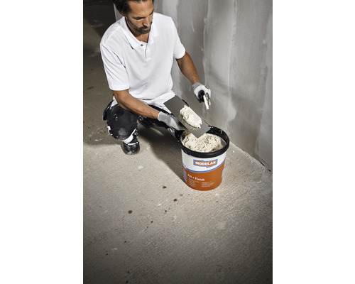 Man neemt plamuur uit een emmer. Geschikt voor pleister- en plamuurwerk.