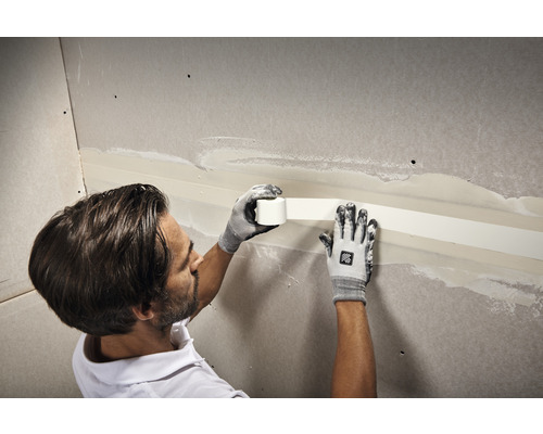 Ambachtsman brengt voegband aan op gipsplaten.