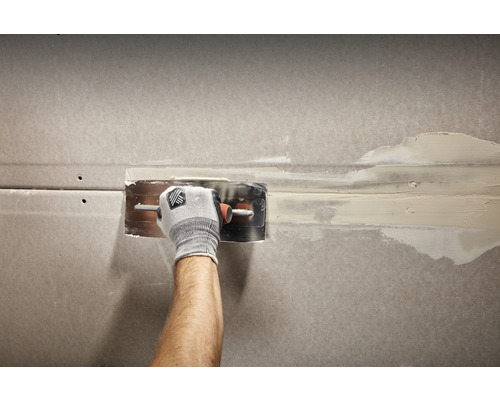 Ambachtsman spatelt een gipsplaatwand glad met een plamuurmes